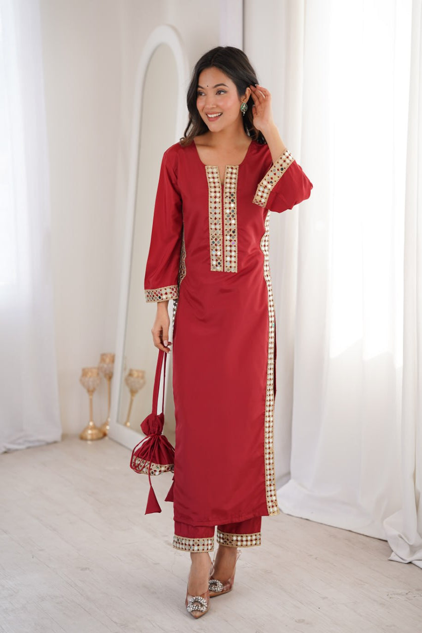 Woman wearing a red traditional outfit with gold embroidery in a white room.